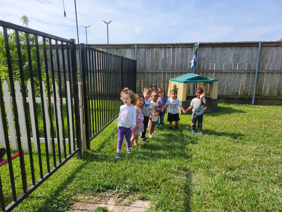 Children holding hands outside on a playground.